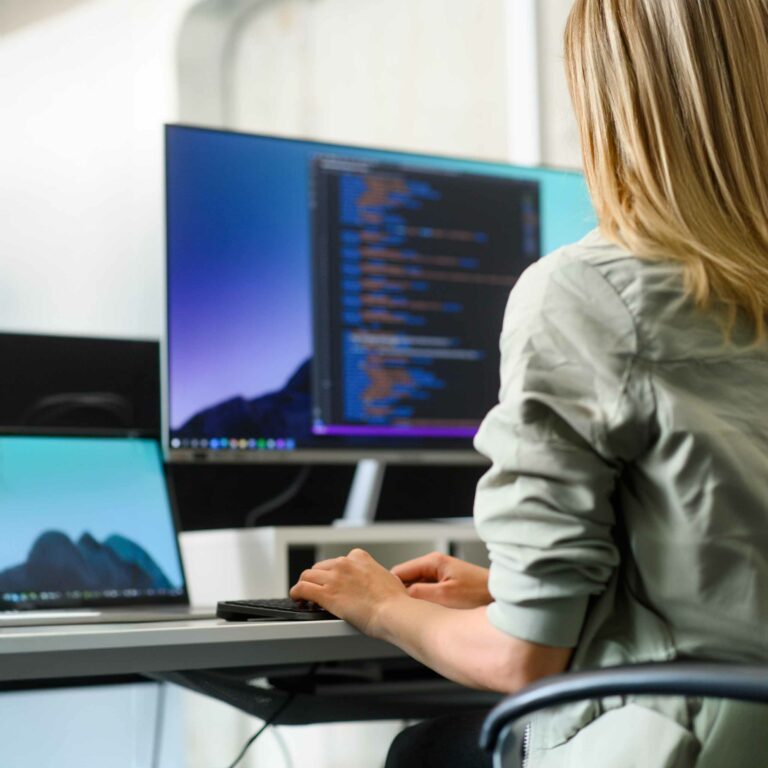 Entwicklerin am Arbeitsplatz mit mehreren Monitoren